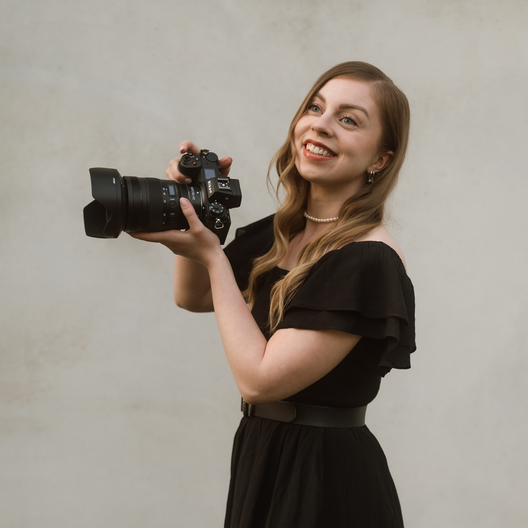 Nainen, jolla on kamera kädessä ja työskentelee valokuvaajana.